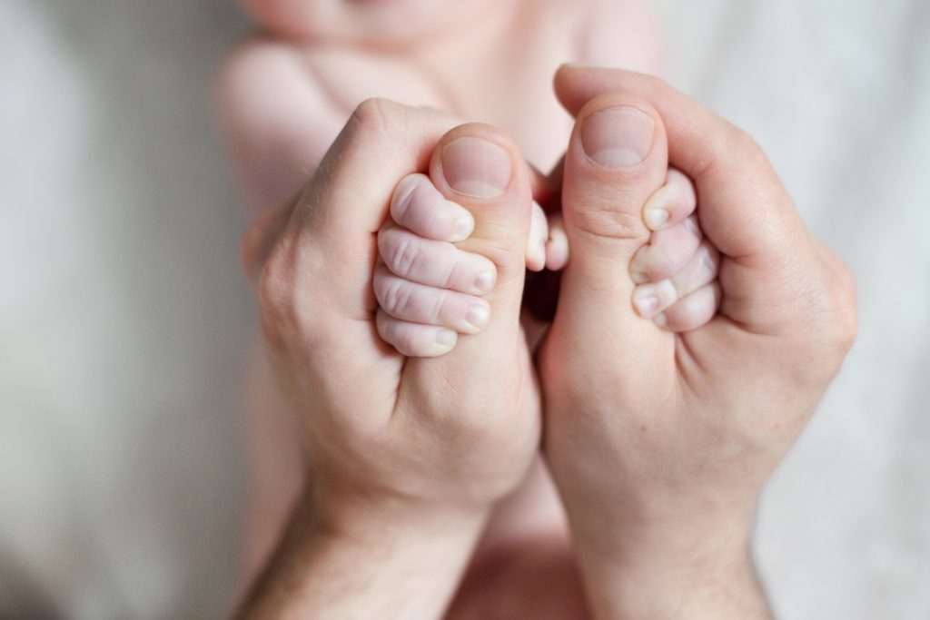 Das Baby spürt die Daumen vom Papa.